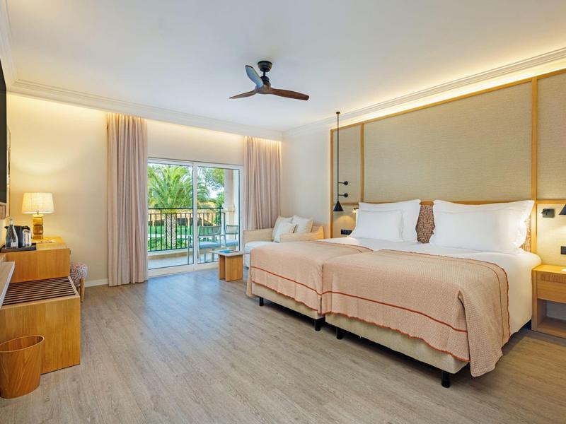 Modernes Hotelzimmer mit zwei Betten, Balkon und natürlichem Licht.