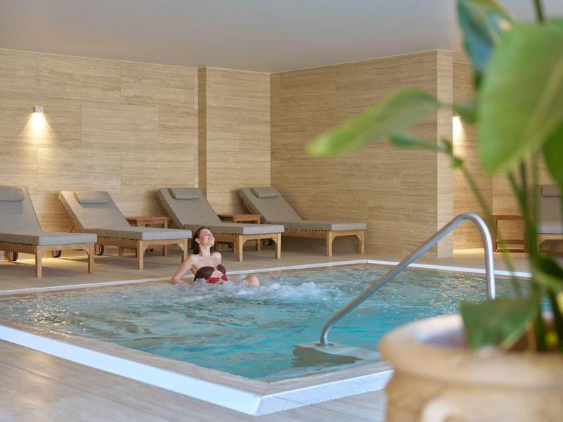 Innenbereich mit Pool, Liegestühlen und entspannter Atmosphäre im Hotel.