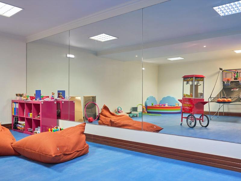 Kinderspielraum mit Kissen, Regalen und Popcornmaschine in hellem, sicherem Bereich.