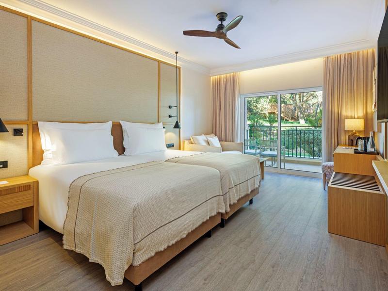 Helles Hotelzimmer mit zwei Betten, Terrassentür und modernem Dekor.