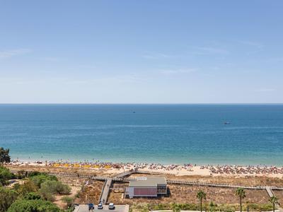 Strand mit Sand und Sonnenschirmen, weiter blauer Ozean und klarer Himmel im Hintergrund.