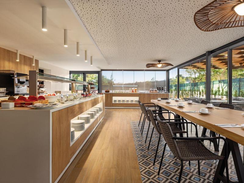 Moderner Essbereich mit Holzmöbeln, langer Tafel, schwarzen Stühlen und großen Fensterfronten.