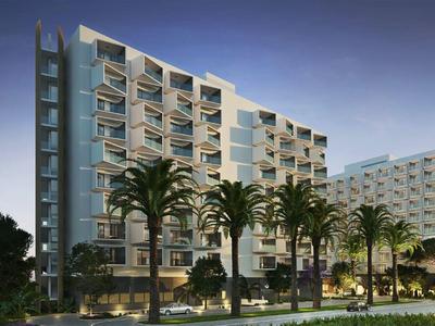 Modernes Hotelgebäude mit Glasfassade, beleuchtet bei Dämmerung, umgeben von Palmen und Grünflächen.