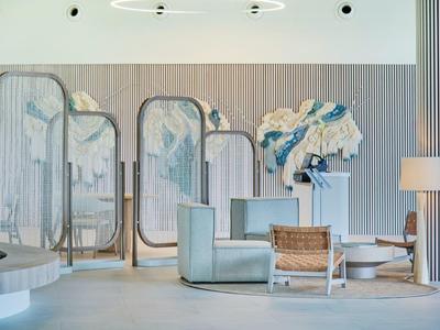 Moderne Lobby mit hellen Sesseln, dekorativen Spiegeln und abstrakter Wandkunst in neutralen Farben.