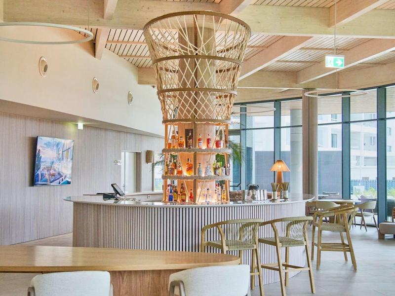 Moderner Gastraum mit Holzdecke, runder Bar und Sitzmöbeln in hellen Naturtönen.