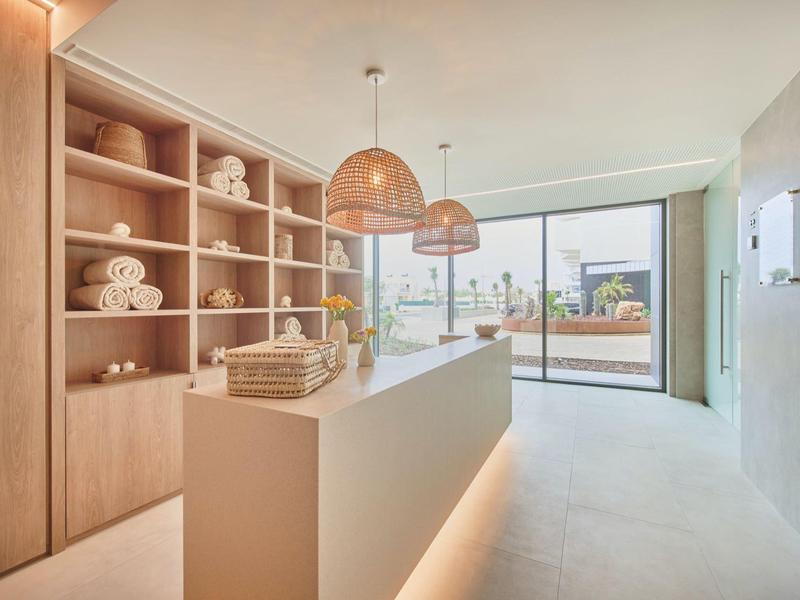 Heller moderner Raum mit Holzregalen, weißen Möbeln und großen Fenstern zur Terrasse.