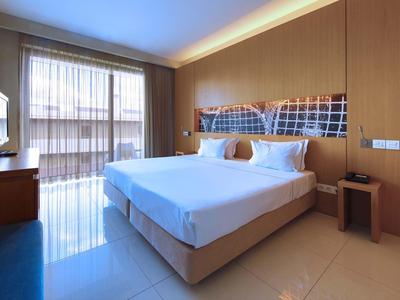 Modernes Hotelzimmer mit großem Bett, Flachbildfernseher und natürlichem Licht durch große Fenster.