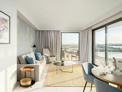 Helles Wohnzimmer mit Sofa, Sesseln, großem Fenster und Meerblick.