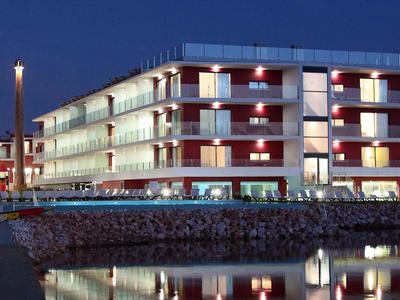 Modernes Hotelgebäude mit beleuchteten Balkonen bei Nacht am Wasser