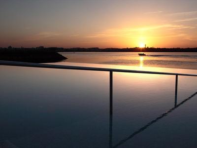 Infinity-Pool bei Sonnenuntergang mit Blick auf einen ruhigen See.