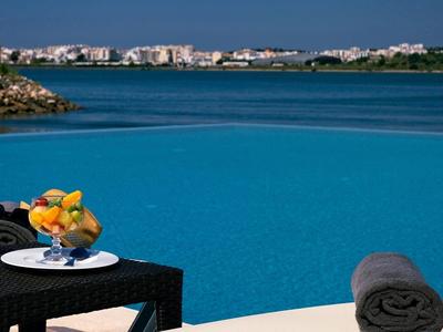 Pool mit Blick auf das Meer, ein Tisch mit Orangensaft und Obst, Handtuch auf Liege