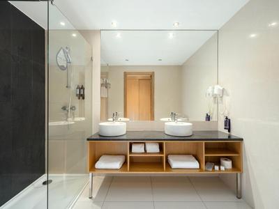 Modernes Badezimmer mit Doppelwaschbecken, großem Spiegel und Dusche mit Glastür.