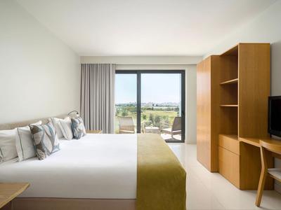 Modernes Hotelzimmer mit zwei Doppelbetten, Holzmöbeln und Blick auf die Landschaft.