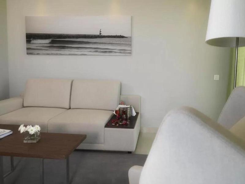 Helles Wohnzimmer mit beigem Sofa, Holztisch und schwarz-weißem Wandbild