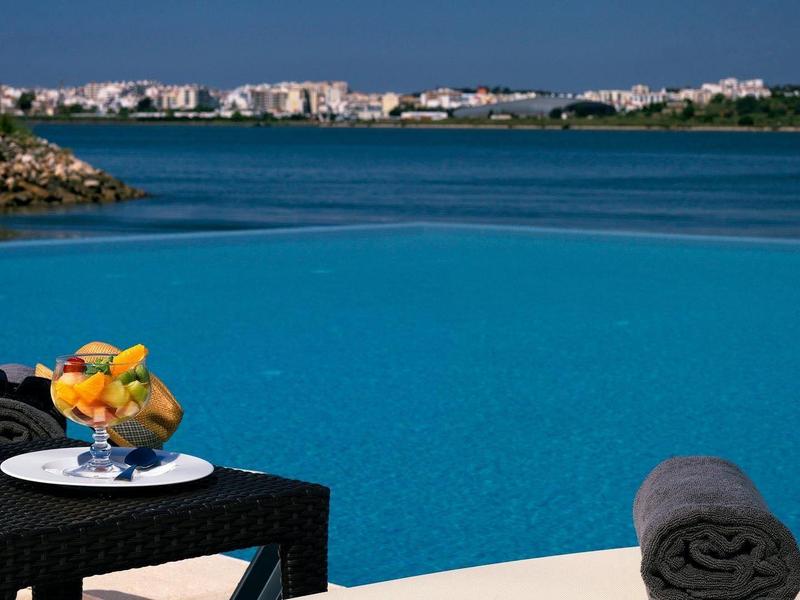 Pool mit Blick auf das Meer, ein Tisch mit Orangensaft und Obst, Handtuch auf Liege