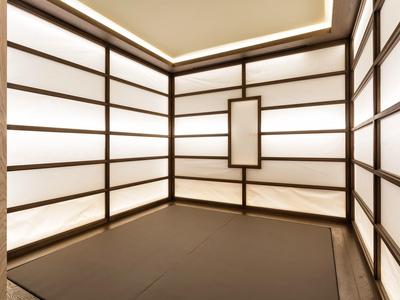 Minimalistischer Raum mit warmem Licht und japanisch inspirierten weißen Wandpaneelen aus Holzrahmen.