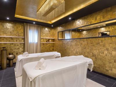 Eleganter Wellnessraum mit zwei Massageliegen, warmen Holzwänden und sanfter Beleuchtung.