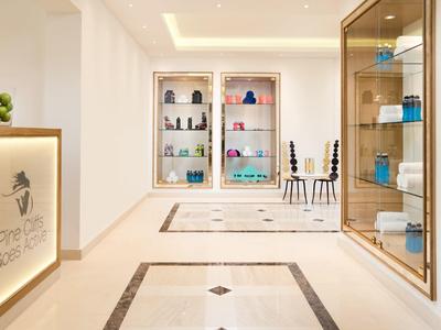 Moderner Flur mit hellen Wänden, Glasvitrinen, dekorativem Teppich und indirekter Deckenbeleuchtung.