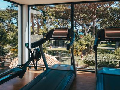 Gym with treadmills in front of large windows overlooking trees and garden.