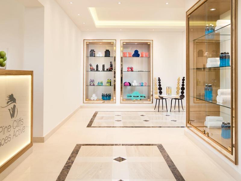 Moderner Flur mit hellen Wänden, Glasvitrinen, dekorativem Teppich und indirekter Deckenbeleuchtung.