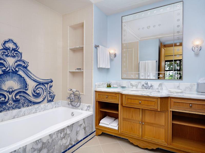 Modernes Badezimmer mit großer Badewanne, blau-weiß gefliest und hölzernem Waschtisch mit großem Spiegel.