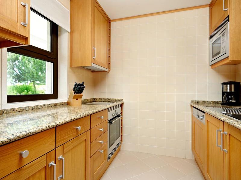 Moderner Strandbereich mit weißen Liegen, Sonnenschirmen und Holzsteg am blauen Meer.