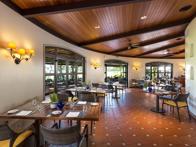 Innenraum eines gemütlichen Restaurants mit Holztischen, Stühlen und warmem Licht.