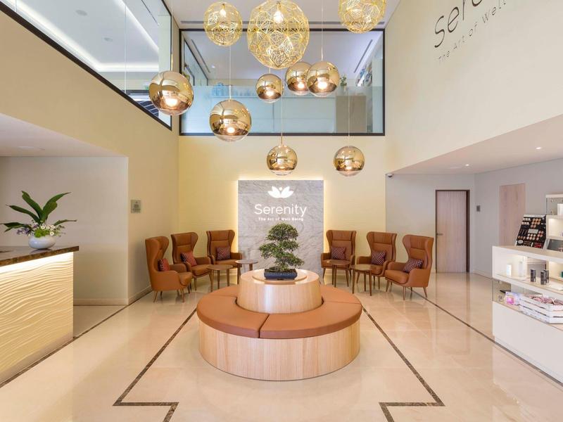 Heller, moderner Hotellobby-Bereich mit Sitzgelegenheiten und dekorativer Pflanzenim Mittelpunkt.