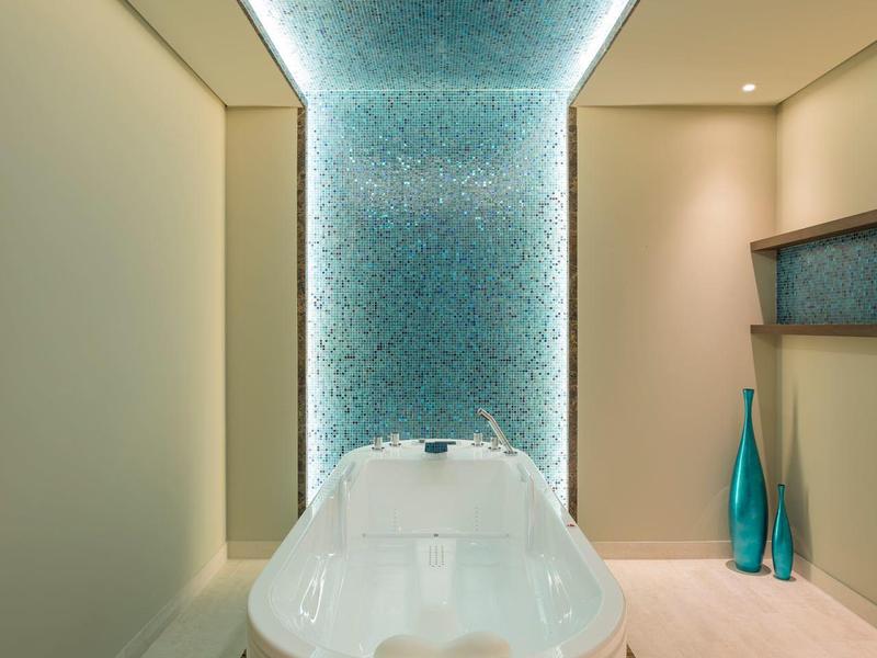 Moderner heller Badezimmerraum mit weißer Badewanne, blauem Mosaikfliesenboden und -decke.