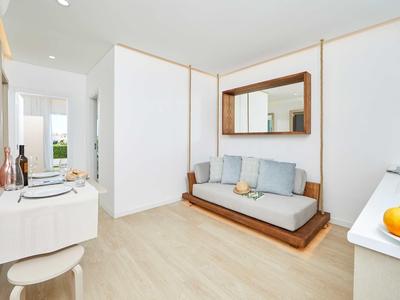 Helles, modern eingerichtetes Wohnzimmer mit hellbraunem Holzboden, grauer Couch und großem Spiegel.