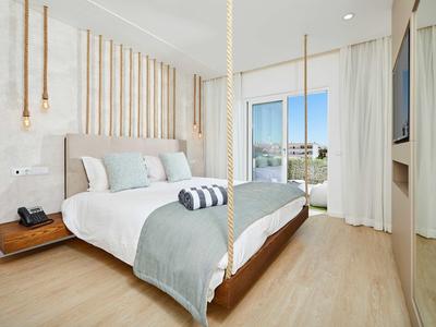 Helles Schlafzimmer mit hängendem Bett, Holzvertäfelung und großem Fenster mit Blick ins Freie.