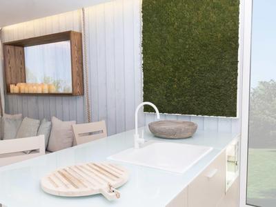 Moderner weißer Küchenblock mit Spüle, Holzschale und Wandspiegel über Stühlen am Fenster.