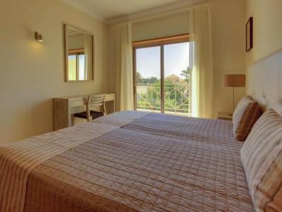 Helles Hotelzimmer mit Doppelbett, Spiegel, Schreibtisch und Balkon mit Blick ins Grüne.