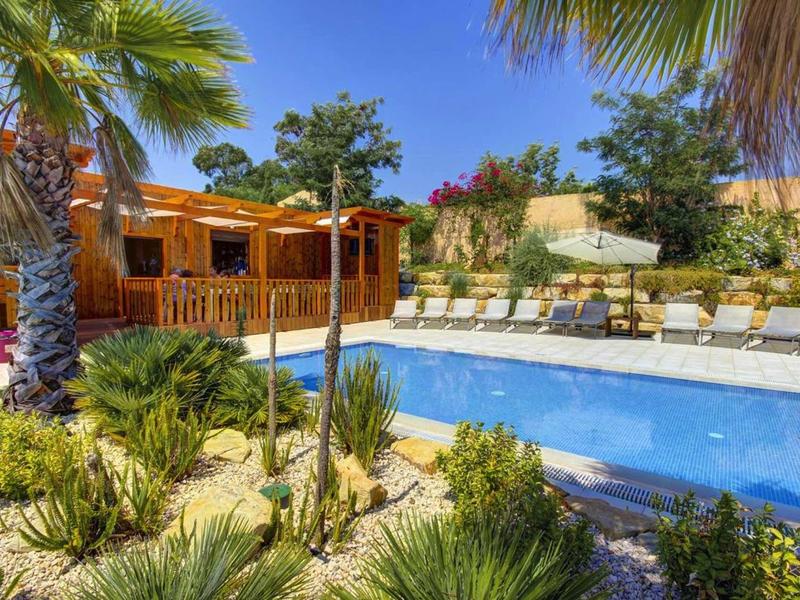 Zwembad met ligstoelen in een tropisch buitenresort bij heldere lucht.