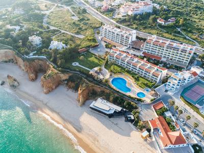 Luchtfoto van een hotel met zwembad aan het kuststrand omringd door groen.