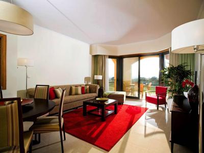 Helles Wohnzimmer mit Sofa, Sesseln und rotem Teppich, Blick auf Balkon