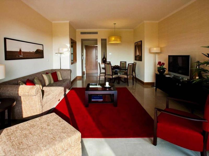 Salon moderne avec canapé, tapis rouge et télévision à écran plat dans une chambre d'hôtel.