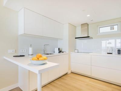 Moderne, helle Küche mit weißen Schränken, Holzfußboden und einfacher, klarer Gestaltung.