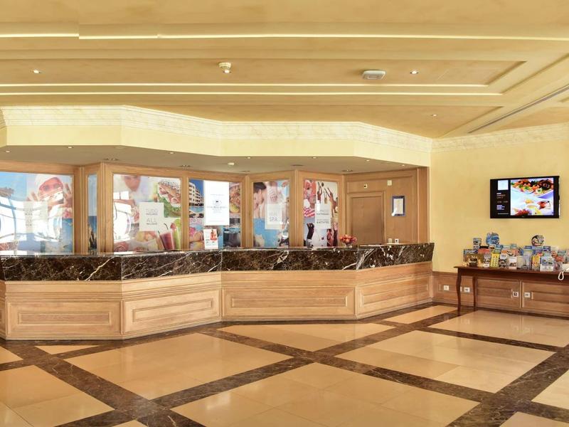 Lichte hotel lobby met receptiebalie van licht hout en zwart marmeren aanrecht