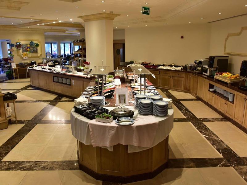 Moderne hotel lounge met buffetstation en gedekte tafels in een lichte ambiance.