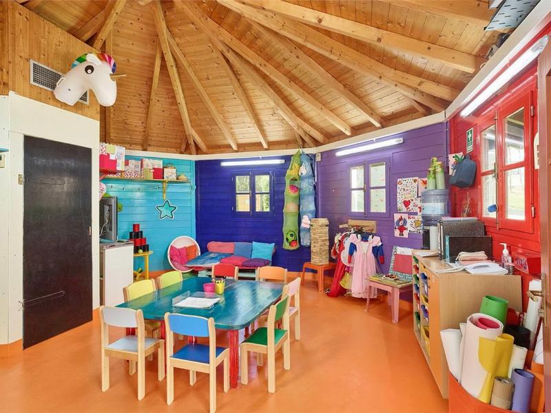 Kleurrijke speelkamer met houten tafel, stoelen en een paardenfiguur in een kinderhotel.