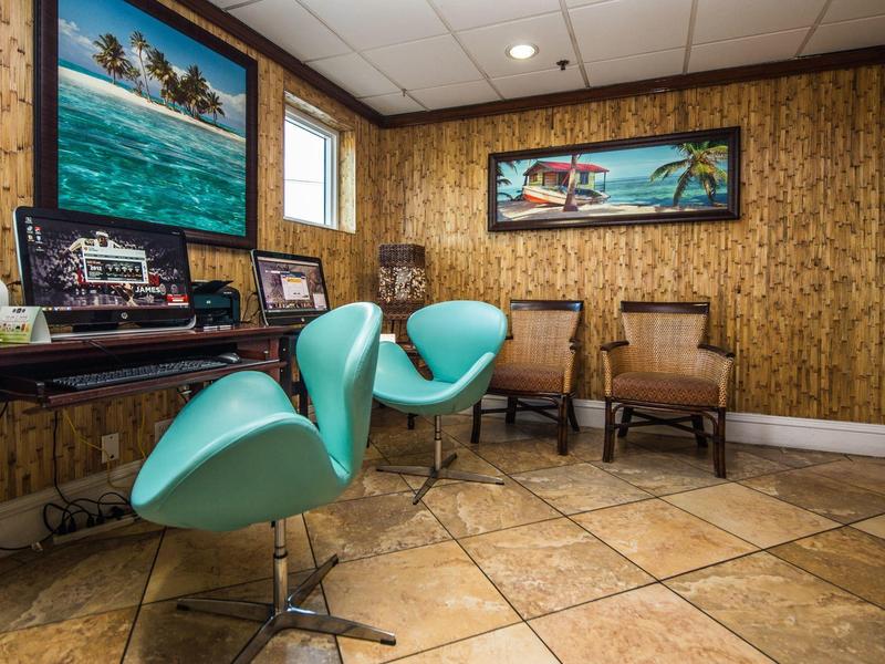 Raum mit türkisen Friseurstühlen, Holzvertäfelung, großen Wandgemälden und beigem Fliesenboden.