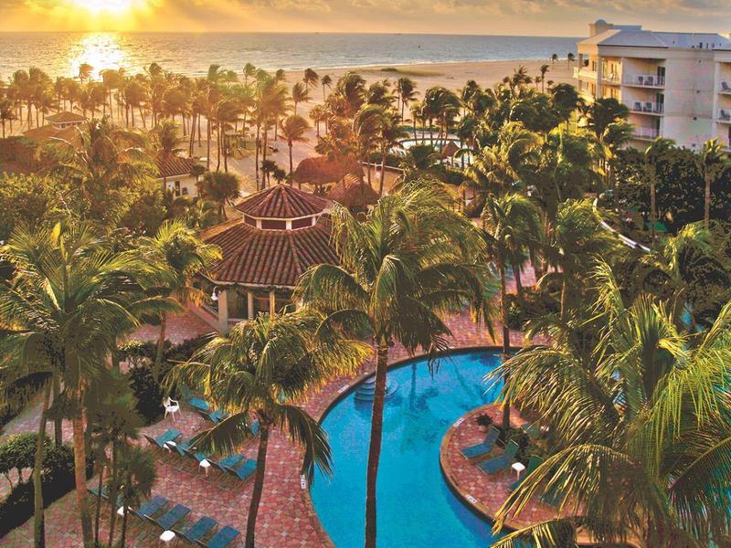 View of a pool with palm trees and sunset at a tropical resort.