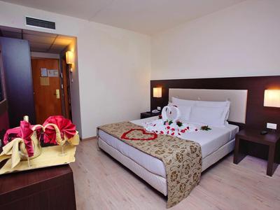 Sauberes, modernes Hotelzimmer mit Doppelbett, Nachttisch, Lampen und dekorativen Handtüchern.