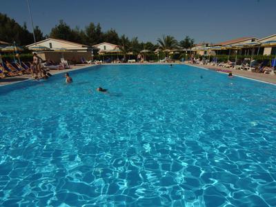 Großes rechteckiges Schwimmbecken mit klarem blauem Wasser, umgeben von Liegestühlen und Sonnenschirmen.