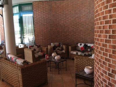 Gemütlicher Sitzbereich mit Korbmöbeln und Kissen vor einer roten Backsteinwand.