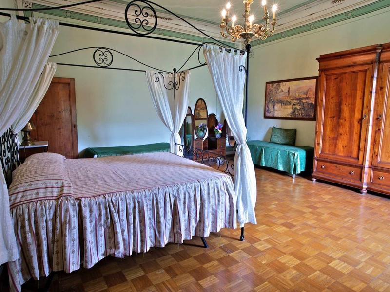 Elegantes Schlafzimmer mit Himmelbett, Holzmöbeln, Parkettboden und pastellgrünen Wänden.