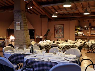 Elegancka restauracja z okrągłymi stołami, niebieskimi tapicerowanymi krzesłami i ciepłym oświetleniem.