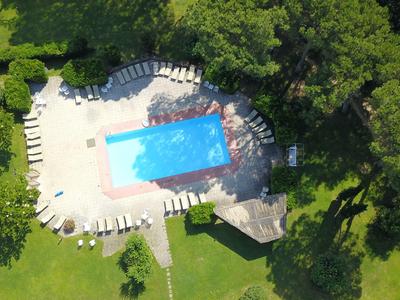 Vogelperspektive auf einen rechteckigen Pool mit Liegestühlen und Bäumen umgeben.