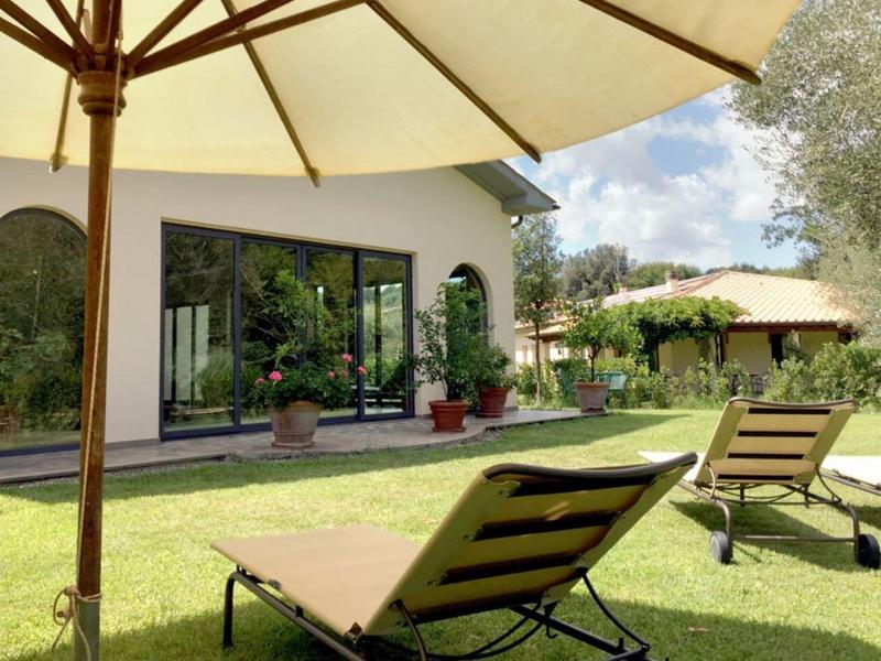 Ogród z leżakami, parasolem i tarasem w słoneczny dzień.